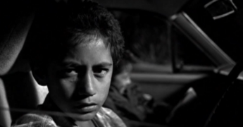 black and white photo of two kids in the front of a car